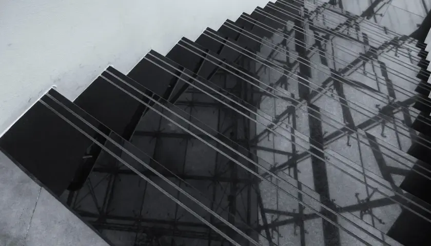 Ciemne schody z polerowanego konglomeratu odbijają architektoniczne detale, tworząc geometryczne wzory.