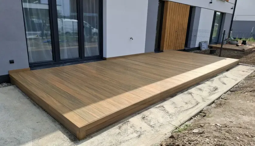 Nowy taras na słupach betonowych, wykonany z desek kompozytowych, stanowi idealne przedłużenie domu.